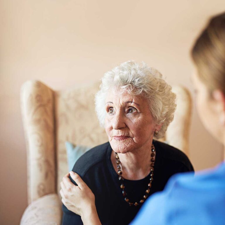Resident and caregiver review a medication list and appointment notes at a table in assisted living.